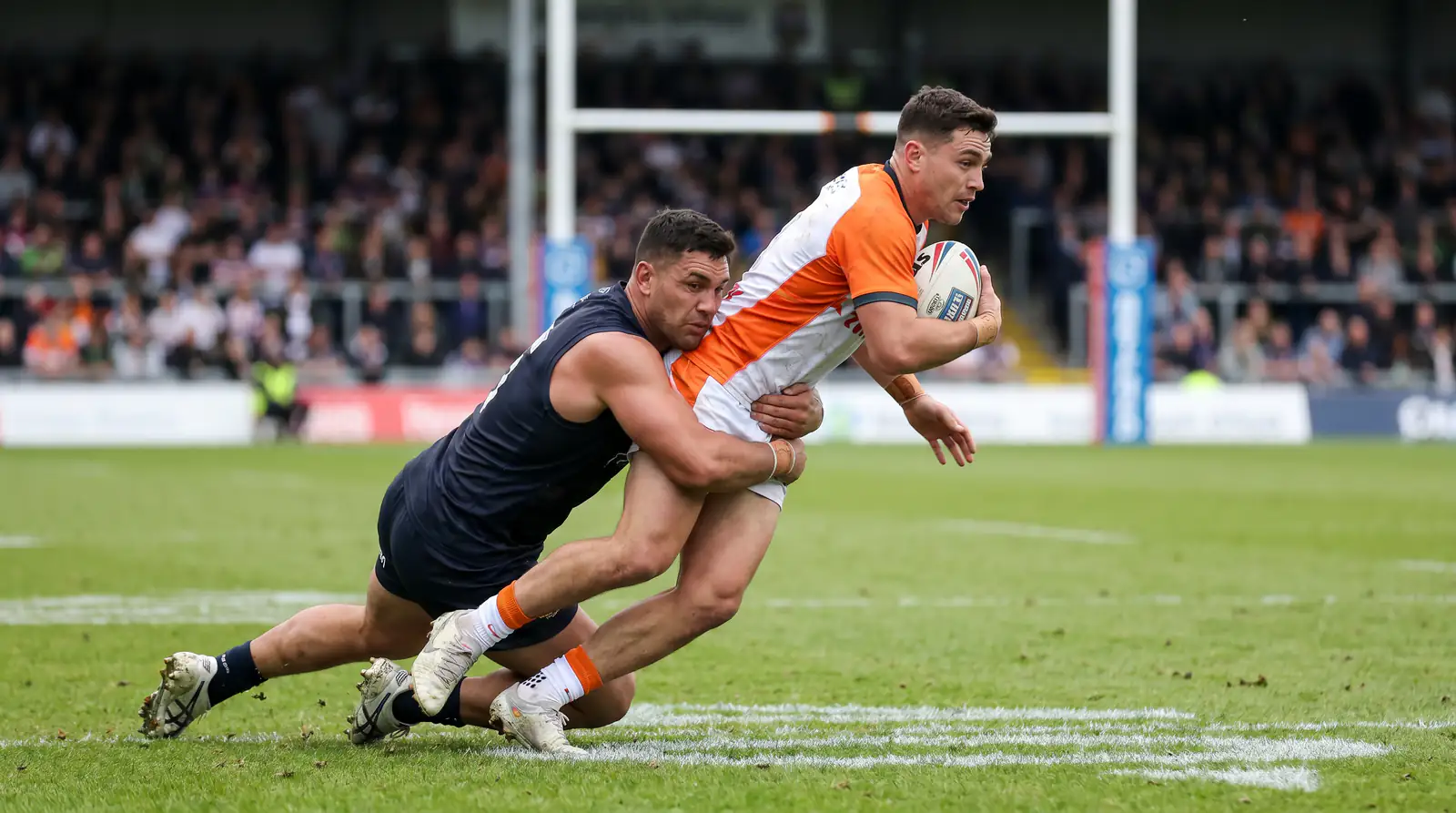 Rugby league defensive tackle by a defender bringing down a ball-carrier during a Super League fixture