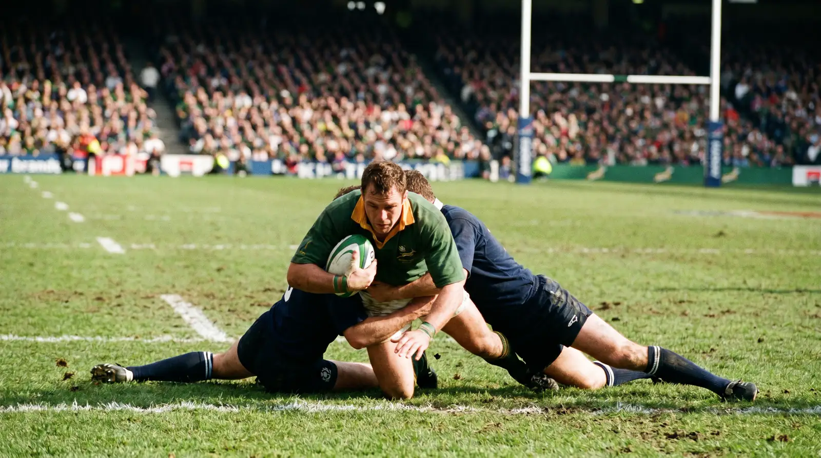 Rugby union knockout round international match with two tackling defenders bringing down a ball-carrier